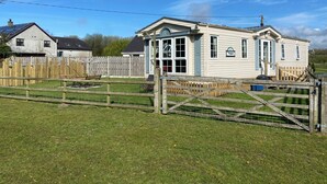 A two-story house with a large front porch and a sign reading "Vogue." - Beautiful 2-bed Chalet in Llanfairpwllgwyngyll (Llanfairpwllgwyngyll)