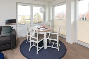 Enjoy meals at the round dining table surrounded by four chairs, with a sofa and flat-screen TV nearby.