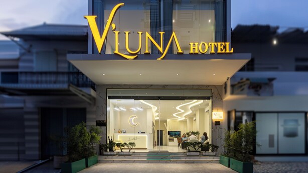 The exterior of the Vluna Hotel with a modern design, featuring a prominent 'Vluna Hotel' sign and a reception area visible through the glass doors. - V'Luna Hotel Can Tho (Can Tho)
