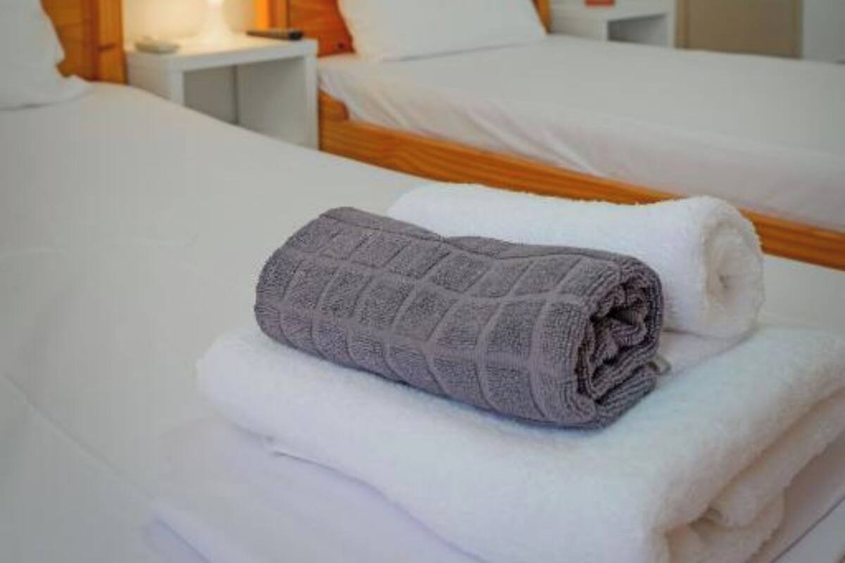 A hotel room with two single beds, each with a wooden headboard, white bedding, and a nightstand with a lamp.