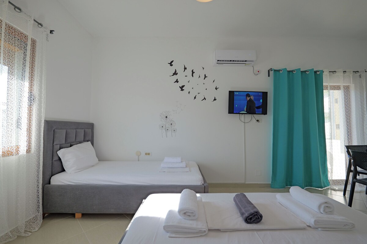 A hotel room with two beds, a TV, and a window with curtains.
