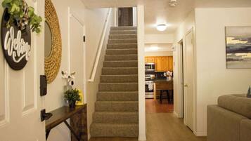 Una escalera conduce a una cocina con armarios de madera y un comedor.