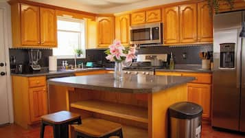 Una cocina con armarios de madera, encimera de granito, refrigerador de acero inoxidable y un fregadero.
