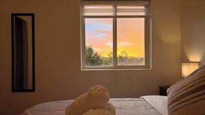 A bedroom with a bed, a window with a sunset view, and a wall-mounted mirror. - Azul Oasis - No house guest without prior approval from host. (Albuquerque)