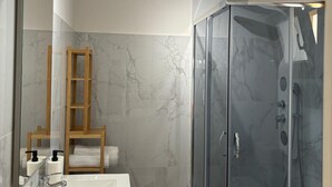 Une salle de bain moderne avec une douche à parois de verre, une échelle en bois et un mur recouvert de carreaux de marbre.