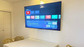Un téléviseur à écran plat fixé au mur, affichant différentes plateformes de diffusion en continu.