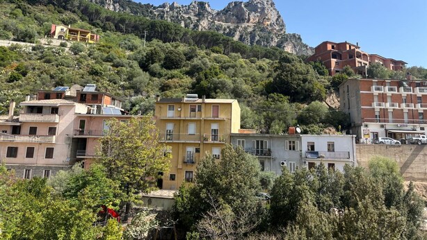 Un quartier résidentiel situé sur une colline, avec des immeubles à plusieurs étages, dont certains sont dotés de balcons, et une falaise rocheuse imposante en arrière-plan.