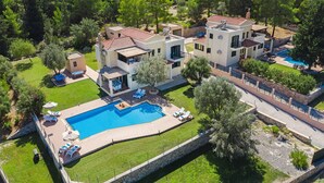 A modern villa with a swimming pool, outdoor seating, and a lush garden.
