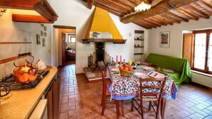 A rustic kitchen with a wooden ceiling, a gas stove, and a dining table set for four. - Agriturismo Bellavista (Radicondoli)