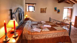 A bedroom with a bed, a nightstand, a lamp, and a chair. - Agriturismo Bellavista (Radicondoli)
