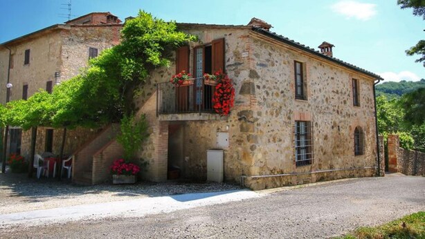 A stone building with a balcony and flower boxes. - Agriturismo Bellavista (Radicondoli)