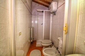 Une salle de bain compacte comprenant une douche, des toilettes et deux lavabos.