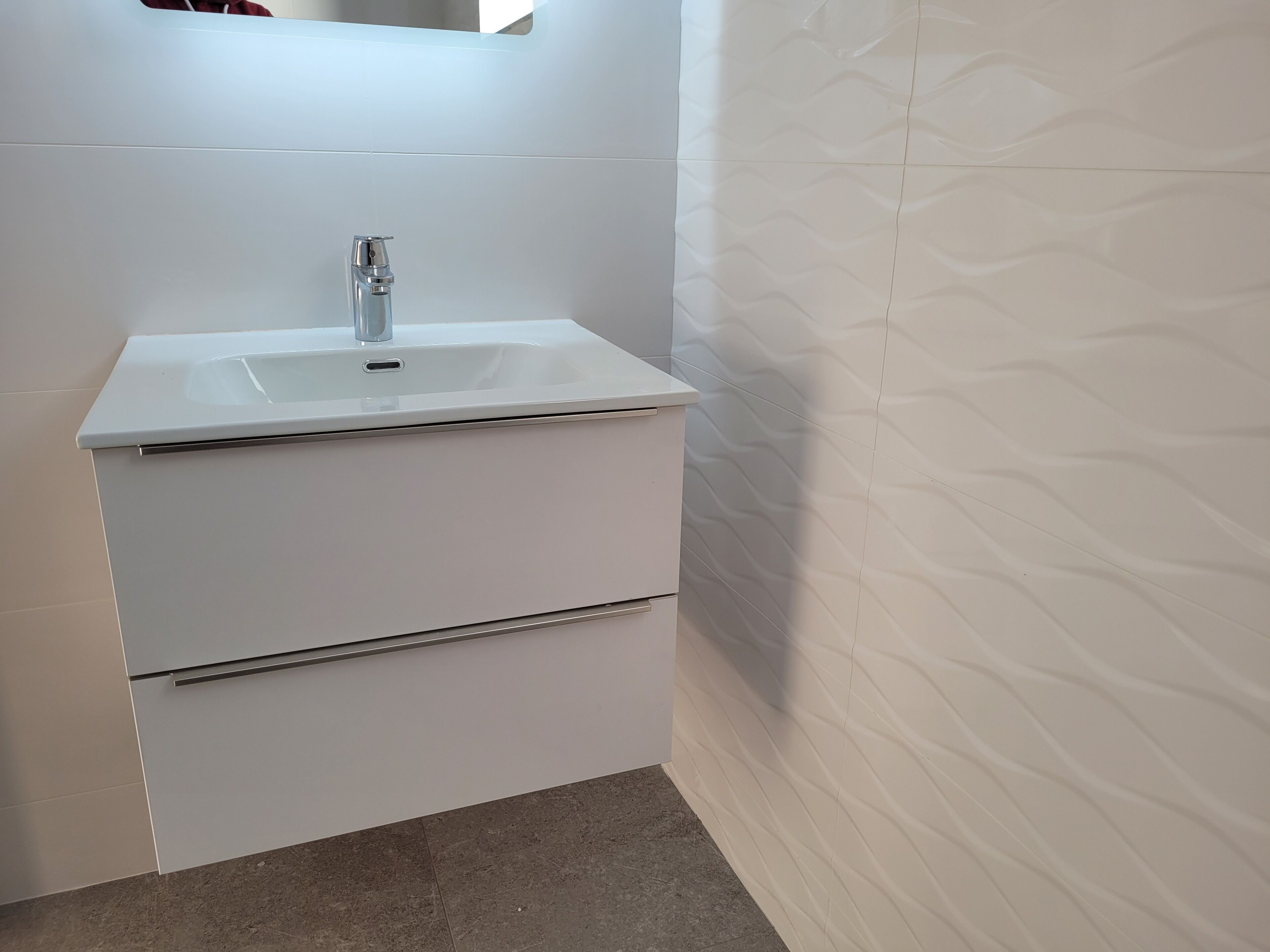 A white bathroom vanity with a sink and two drawers.
