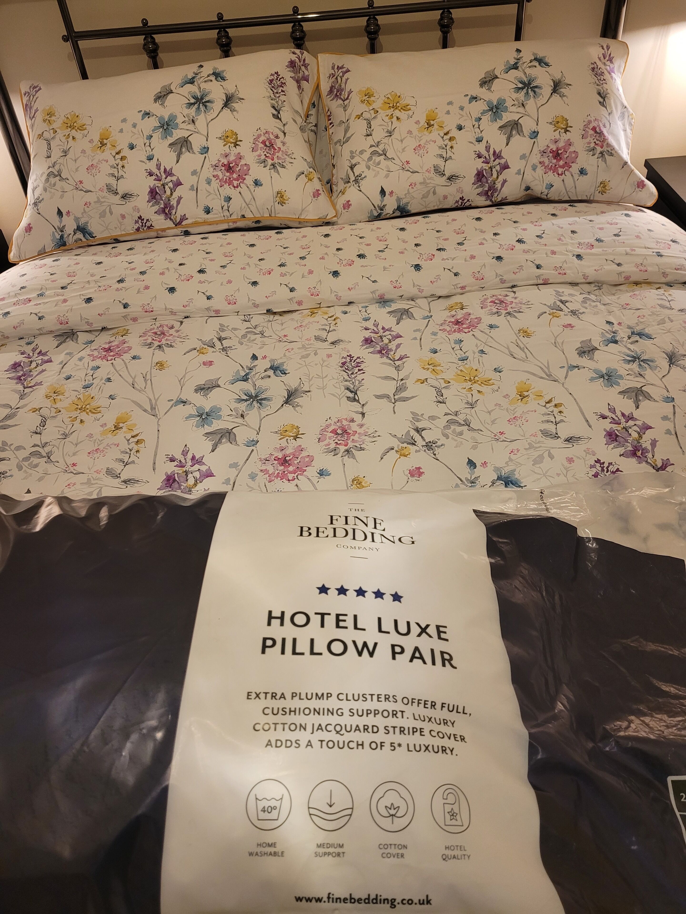 En hotelseng med dyne og puder i et blomsteret mønster.