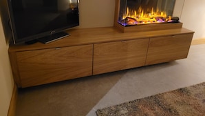 A wooden entertainment unit with a flat-screen TV and a built-in fireplace. - Immaculate 2-bed Cottage in Tuam (Polladooey)
