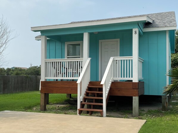 A small, single-story house with a front porch and a staircase leading to the entrance.