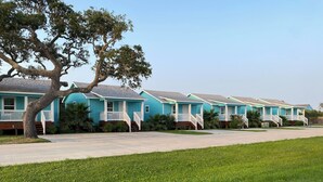 Una hilera de casas azules con barandillas blancas y un árbol en primer plano.