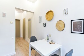Une pièce moderne avec une table blanche, des chaises et une petite plante en pot.