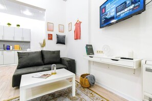 Un salon moderne avec un canapé noir, une table basse blanche et un téléviseur fixé au mur diffusant du contenu Netflix.