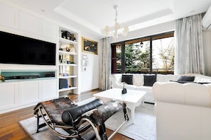 Relax in a stylish living room with a sofa set, armchair, and flat-screen TV, offering a view of the outdoors.