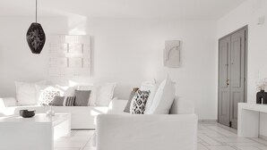 Ein modernes, minimalistisches Wohnzimmer mit einem weißen Sofagarnitur, einem Couchtisch und einer hängenden Pendelleuchte.