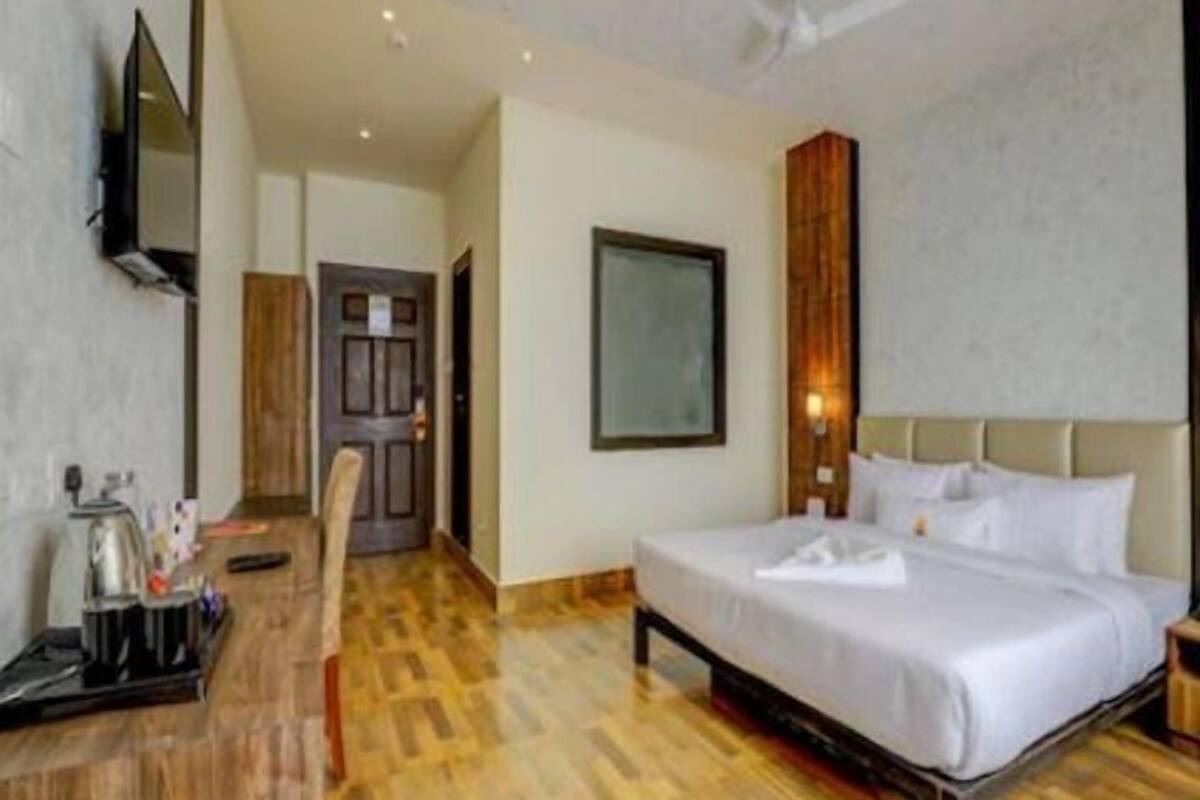 Quarto de hotel com uma cama, mesa de cabeceira e televisão.