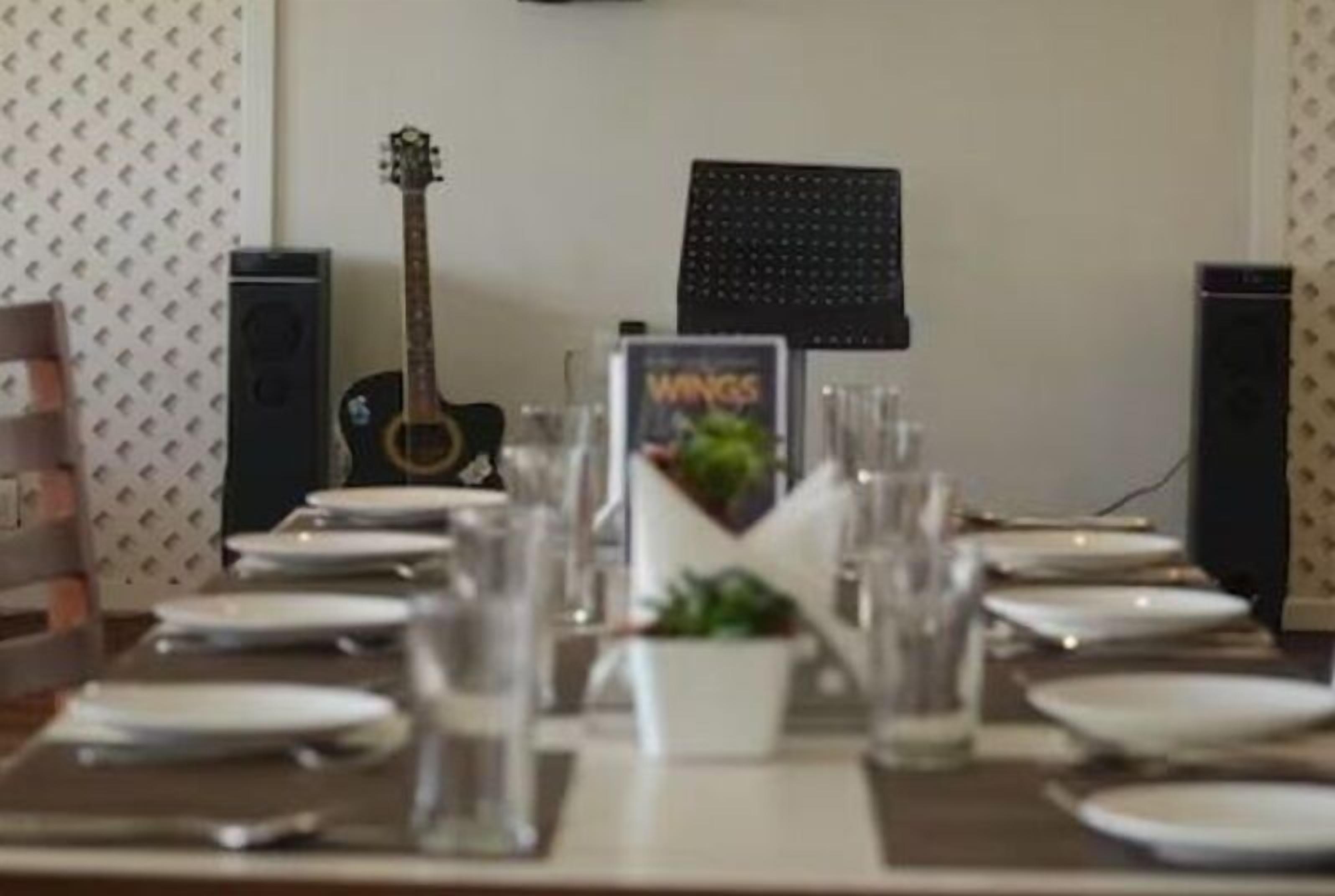 A dining table set with plates, glasses, and a menu stand.