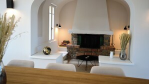 A modern living room with a stone fireplace, white walls, and a wooden table.