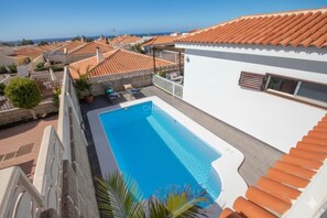 Une piscine sur le toit offrant une vue sur la mer, des toits en tuiles rouges et un bâtiment blanc doté d’un balcon.
