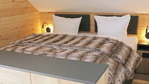A modern bedroom with a wooden ceiling, a bed with white bedding, and two bedside lamps.