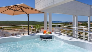 Ein Whirlpool mit Blick auf die Landschaft, ein Tisch mit Obst und Getränken und ein Strand im Hintergrund.