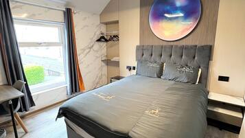 A modern bedroom with a large bed, a round wall decoration, a built-in wardrobe, and a view through a window.