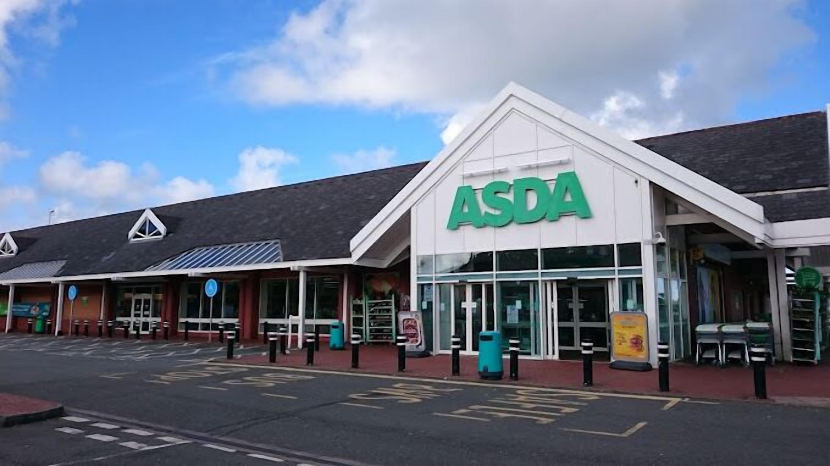 Suuri ASDA-tavaratalo, jossa on selkeästi näkyvä vihreä logo, katettu sisäänkäynti ja merkityillä paikoilla varustettu parkkipaikka.