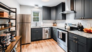 Una cocina moderna con armarios oscuros, electrodomésticos de acero inoxidable y piso de madera.