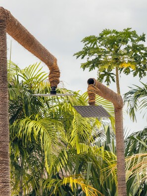 A cat tree with a scratching post and a hanging toy, surrounded by lush green palm trees. - Ayras Hotel Zanzibar (Paje)