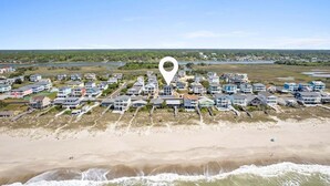 Luchtbeeld van een kustwoongebied met huizen aan het strand, een heldere lucht en een kalme zee.