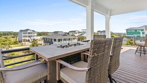 Een overdekt terras buiten met een tafel en stoelen, met uitzicht op een woongebied.