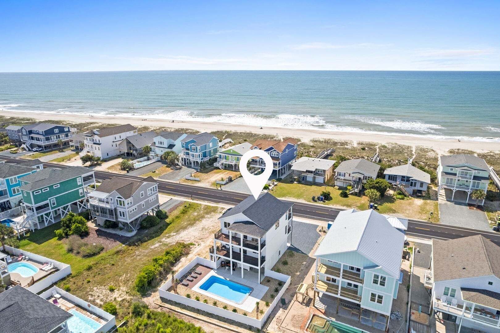 A coastal residential area with houses, a swimming pool, and a beach.