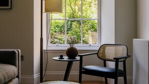 A corner room with a large window, a floor lamp, a chair, a small table with a vase and a book, and a radiator. - 33 Castle Terrace (Edinburgh)