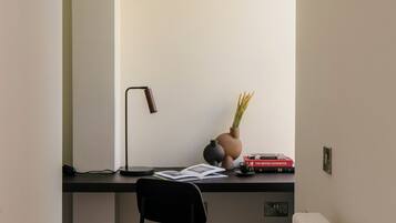 A minimalist office space with a desk, chair, lamp, and radiator.