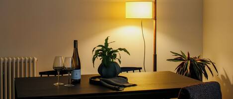 A dining table with two wine glasses, a bottle of wine, and two potted plants.