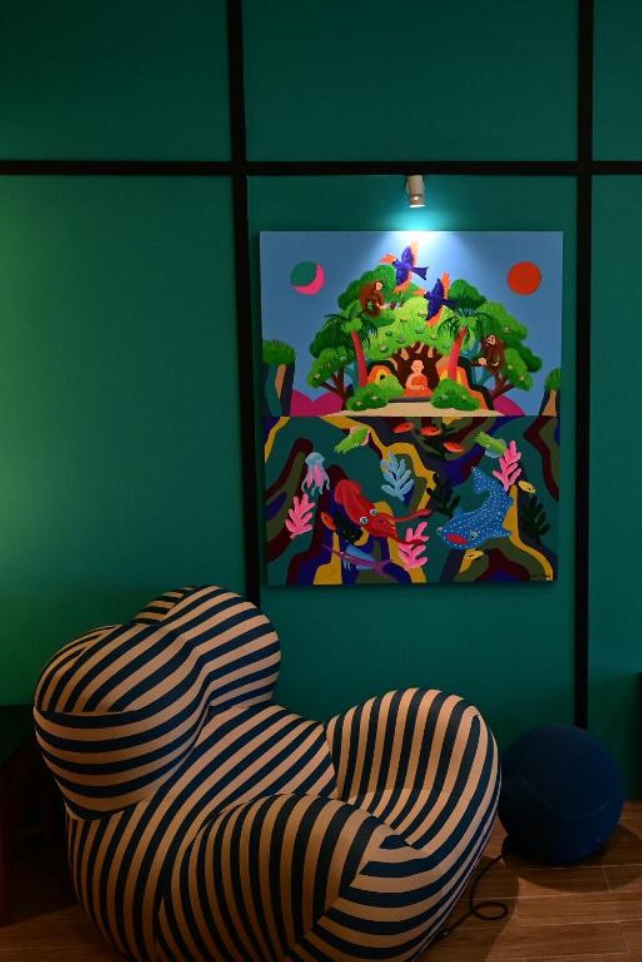 A room with a colorful abstract painting on the wall, a striped chair, and a blue object on the floor.