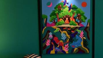 A room with a colorful abstract painting on the wall, a striped chair, and a blue object on the floor.