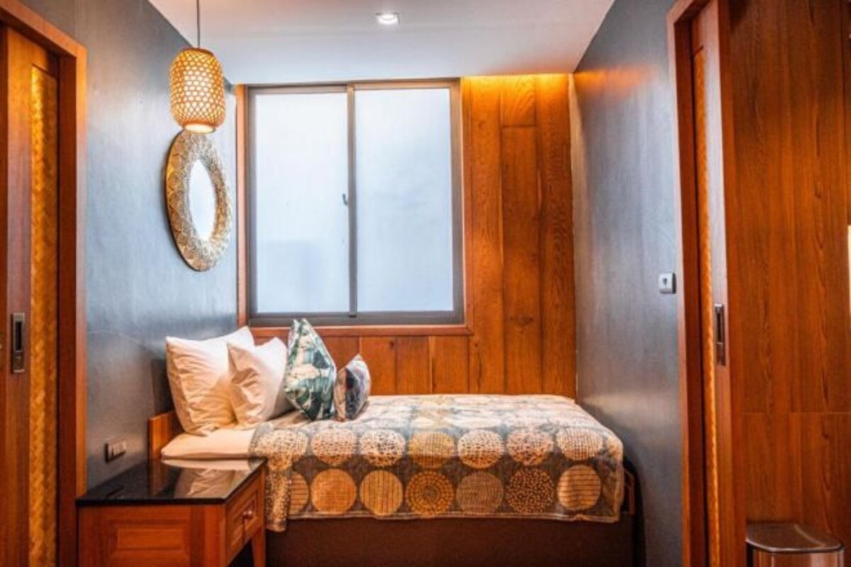 Un dormitorio con cama, ventana y paredes de madera.