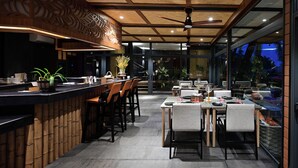 A modern restaurant with a bar area, outdoor seating, and a view of the night sky. - Big Sun Residence by iRETREAT (Ko Yao)