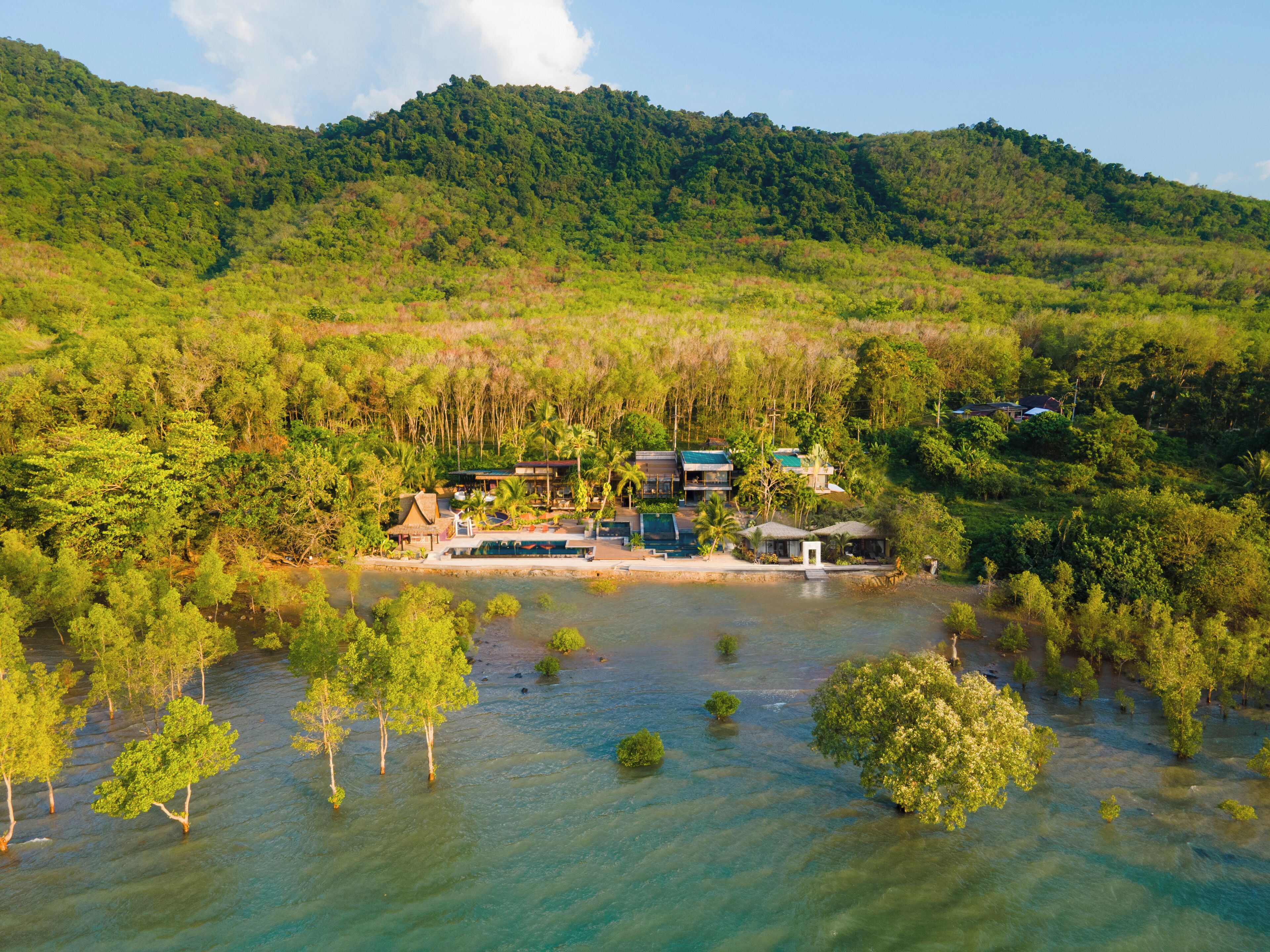 A resort with multiple buildings surrounded by lush greenery and a river.