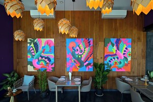 Un comedor con paredes de madera, pinturas abstractas coloridas e iluminación colgante moderna.