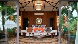 A modern living room with a white sofa, patterned cushions, a round coffee table, and a large mirror on the wall. - Big Sun Residence by iRETREAT (Ko Yao)