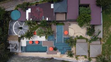 Vue aérienne d’un complexe hôtelier doté d’une piscine, d’un espace de détente en plein air et d’une plage.