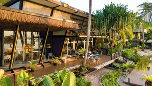 A modern resort with a thatched-roof outdoor area, glass-enclosed dining, and lush tropical landscaping. - Big Sun Residence by iRETREAT (Ko Yao)
